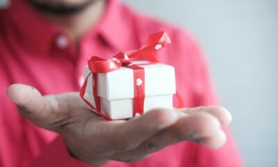 Мъж държи бяла подаръчна кутия с червена панделка