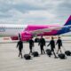 Кабинен екипаж на Wizz Air върви по пистата към самолет